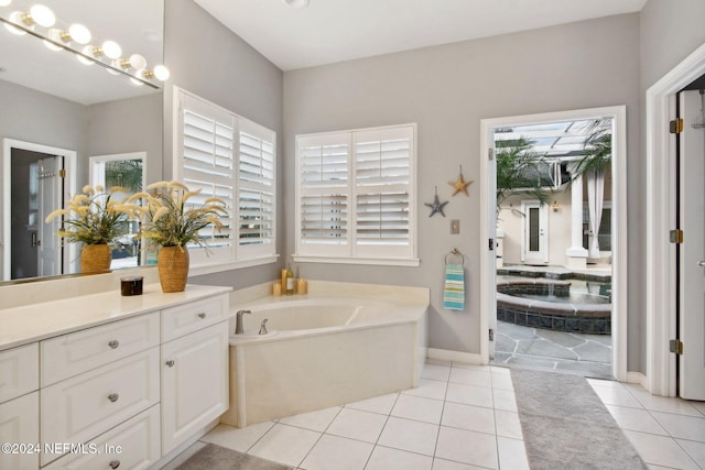 bathroom with tile patterned floors, tiled tub, and vanity