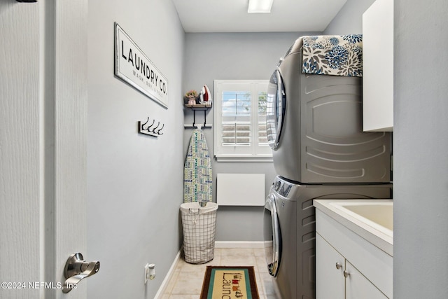 washroom featuring cabinets, light tile patterned floors, and stacked washer / dryer