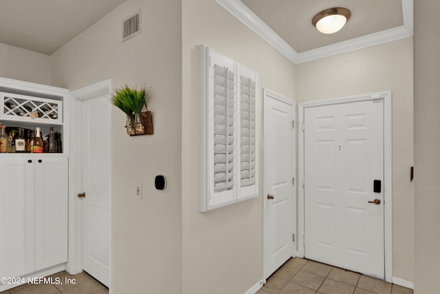 entrance foyer featuring crown molding and light tile patterned floors