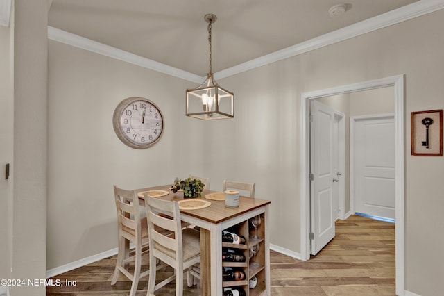 dining area with light hardwood / wood-style floors, crown molding, and a chandelier