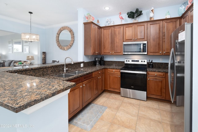 kitchen with appliances with stainless steel finishes, brown cabinets, a sink, a peninsula, and an inviting chandelier