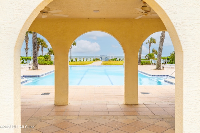 view of pool with a patio area, a water view, and ceiling fan