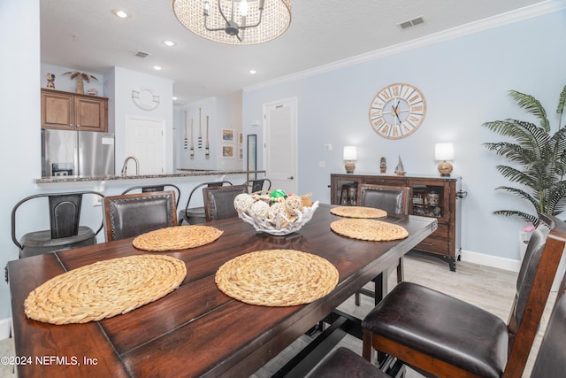 dining space featuring sink, crown molding, a textured ceiling, and an inviting chandelier