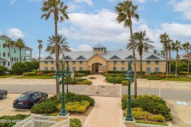 view of front of property with a standing seam roof, stucco siding, uncovered parking, and metal roof