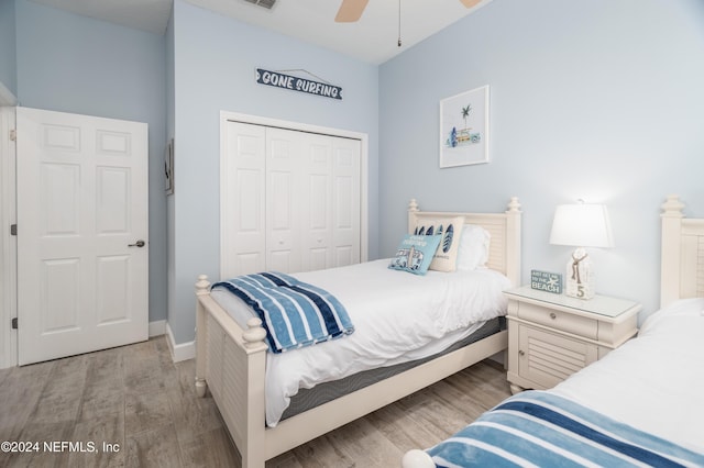 bedroom with ceiling fan, a closet, wood finished floors, and visible vents