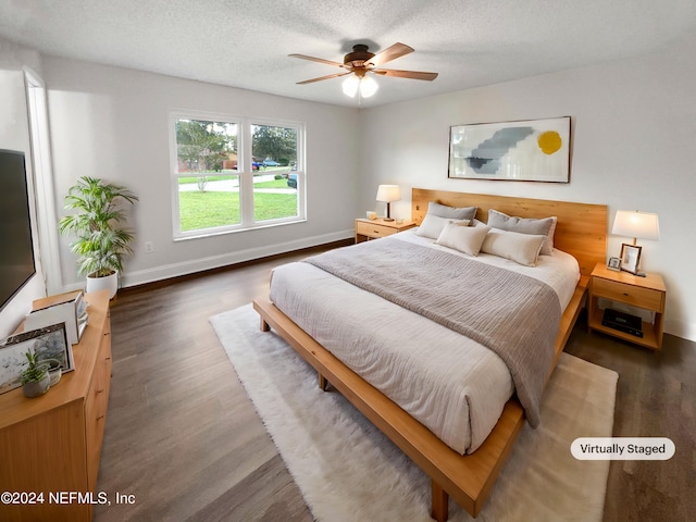 bedroom with a textured ceiling, ceiling fan, and dark hardwood / wood-style flooring