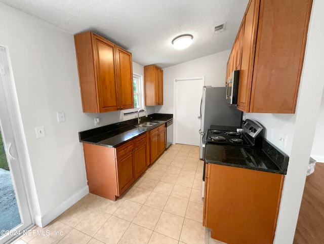 kitchen featuring a textured ceiling, stove, sink, and light tile patterned floors