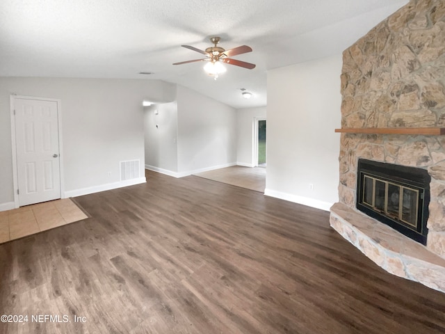 unfurnished living room with ceiling fan, a textured ceiling, vaulted ceiling, dark wood-type flooring, and a fireplace