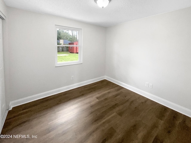 spare room with a textured ceiling and dark hardwood / wood-style floors