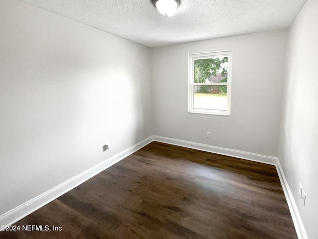 unfurnished room featuring dark hardwood / wood-style floors and a textured ceiling