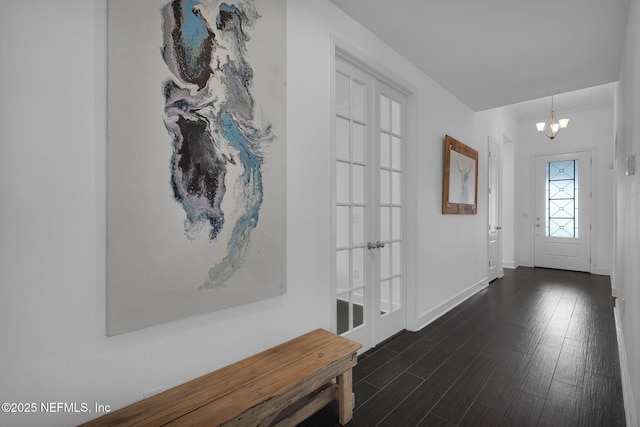 foyer entrance with dark hardwood / wood-style floors, a chandelier, and french doors