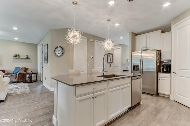 kitchen featuring white cabinetry, sink, hanging light fixtures, a kitchen island with sink, and stainless steel appliances