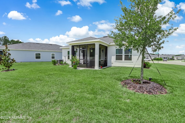 rear view of house with a sunroom and a yard