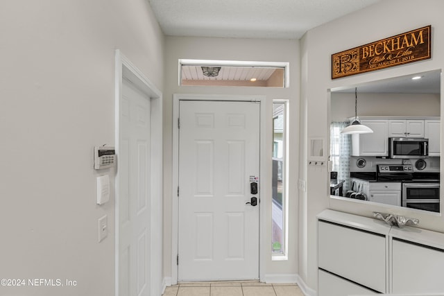 entryway with a textured ceiling and light tile patterned flooring