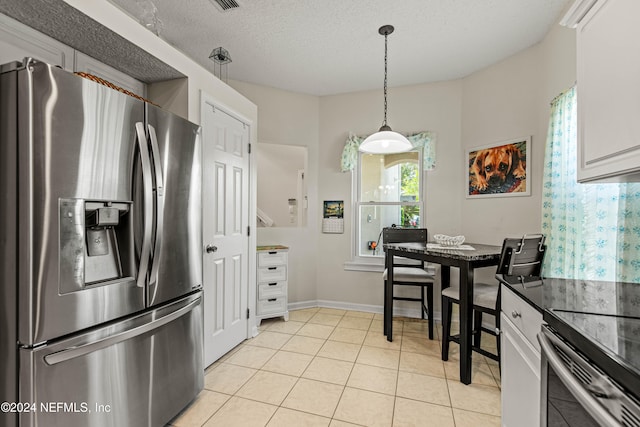 kitchen featuring hanging light fixtures, appliances with stainless steel finishes, white cabinetry, a textured ceiling, and light tile patterned flooring