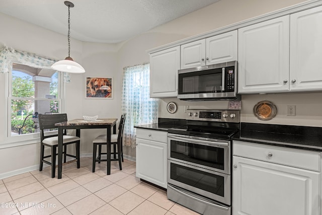 kitchen with appliances with stainless steel finishes, white cabinetry, and light tile patterned floors