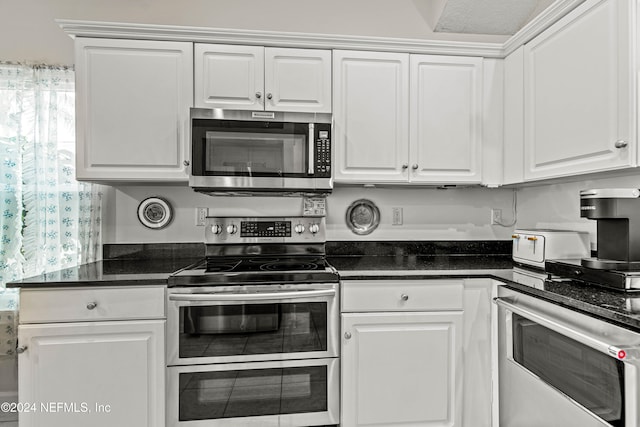 kitchen featuring white cabinets, a healthy amount of sunlight, stainless steel appliances, and dark stone counters