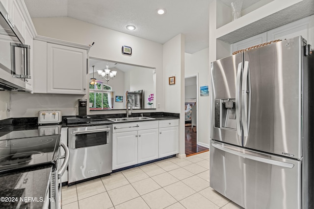 kitchen featuring lofted ceiling, sink, light tile patterned flooring, white cabinetry, and appliances with stainless steel finishes