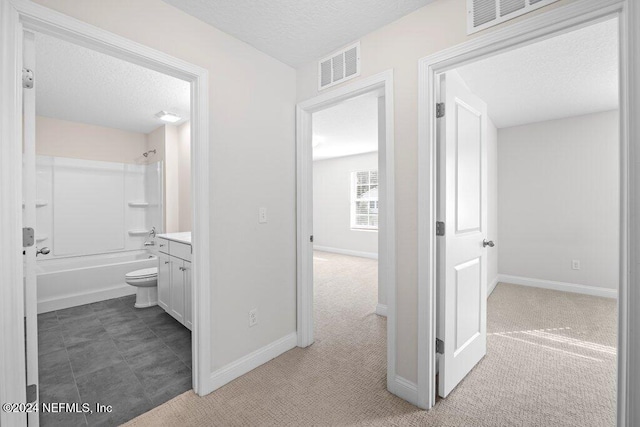 corridor featuring a textured ceiling and light colored carpet