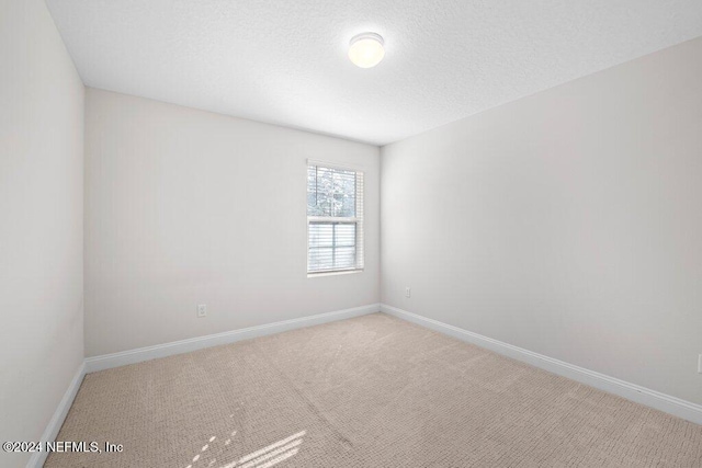 carpeted empty room featuring a textured ceiling