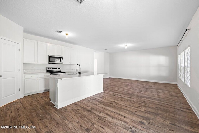 kitchen with appliances with stainless steel finishes, white cabinetry, dark wood-type flooring, and an island with sink