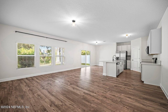 kitchen with a center island with sink, stainless steel appliances, a wealth of natural light, and dark hardwood / wood-style flooring