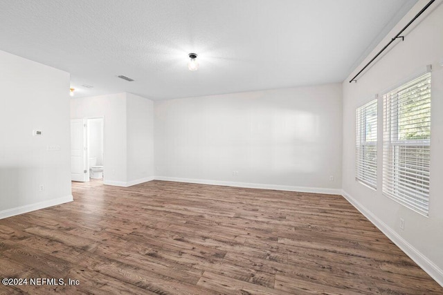 unfurnished room with dark wood-type flooring and a textured ceiling