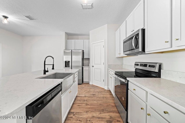 kitchen with sink, a textured ceiling, light hardwood / wood-style floors, stainless steel appliances, and white cabinets