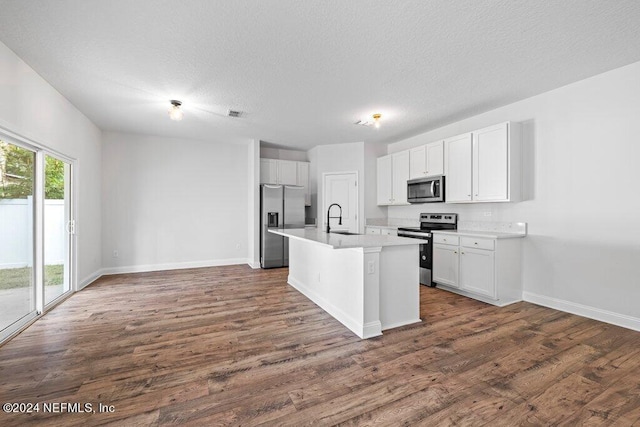 kitchen featuring dark hardwood / wood-style flooring, appliances with stainless steel finishes, an island with sink, white cabinetry, and sink