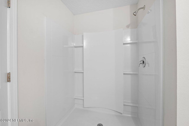 bathroom with a textured ceiling and a shower