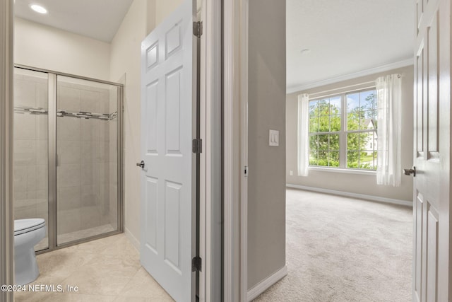 bathroom with a shower with door, toilet, and ornamental molding