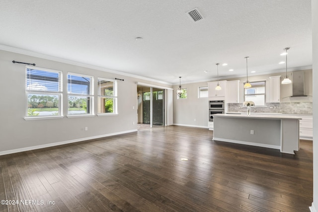 unfurnished living room featuring ornamental molding, a textured ceiling, and dark wood-type flooring