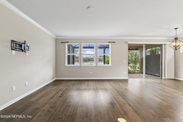 spare room featuring ornamental molding, a notable chandelier, a textured ceiling, and dark wood-type flooring