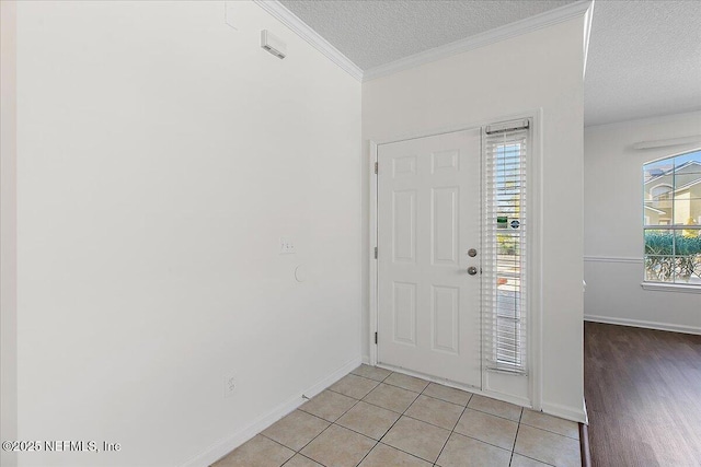 foyer with ornamental molding, a textured ceiling, and light tile patterned flooring