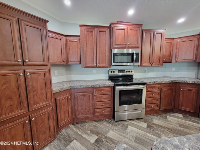 kitchen with ornamental molding, appliances with stainless steel finishes, and light hardwood / wood-style floors