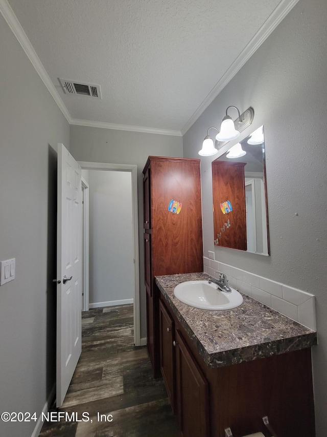 bathroom featuring vanity, crown molding, hardwood / wood-style flooring, and a textured ceiling