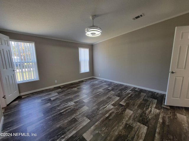 spare room featuring dark wood-type flooring and crown molding