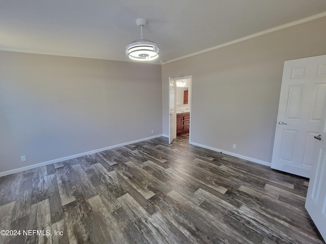 spare room with dark wood-type flooring and crown molding