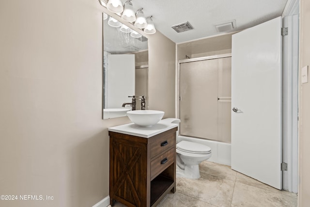 full bathroom featuring vanity, bath / shower combo with glass door, a textured ceiling, and toilet