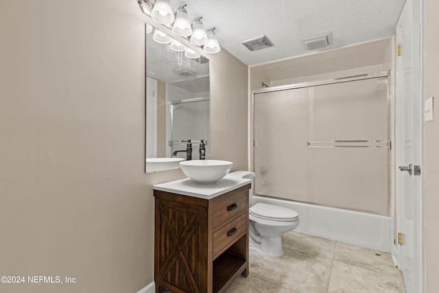 full bathroom featuring vanity, combined bath / shower with glass door, a textured ceiling, and toilet