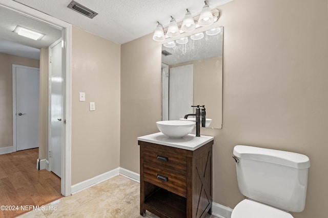 bathroom with toilet, a textured ceiling, vanity, and wood-type flooring