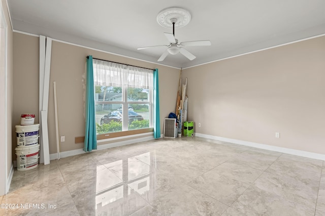 empty room featuring ceiling fan and crown molding