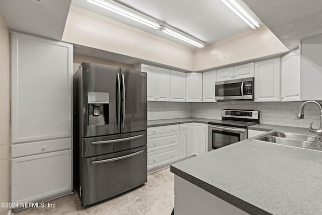 kitchen with white cabinets, stainless steel appliances, sink, and backsplash