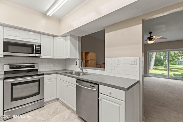 kitchen featuring white cabinets, tasteful backsplash, stainless steel appliances, sink, and light colored carpet