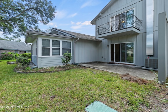 rear view of property with a yard, a patio area, and a balcony