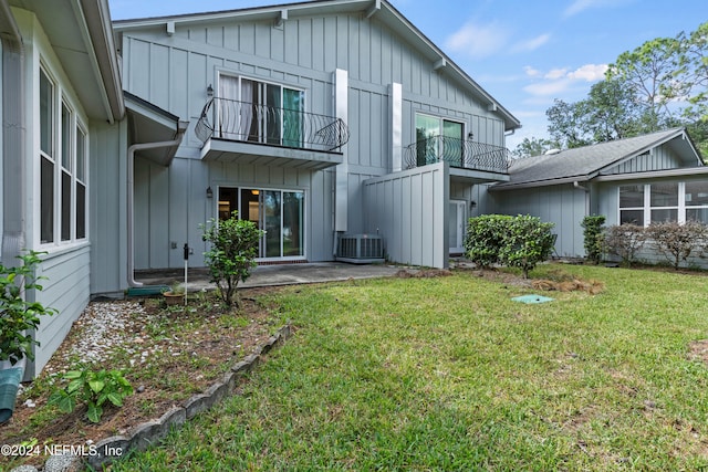 rear view of house featuring a balcony, central AC, a patio area, and a lawn