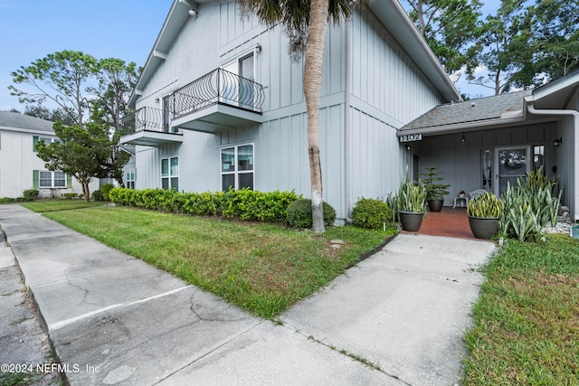 view of property exterior featuring a lawn and a balcony