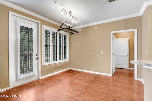 unfurnished dining area with ornamental molding, light hardwood / wood-style flooring, and a textured ceiling