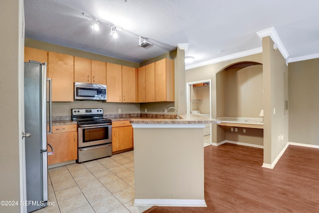 kitchen with ornamental molding, a textured ceiling, kitchen peninsula, and stainless steel appliances