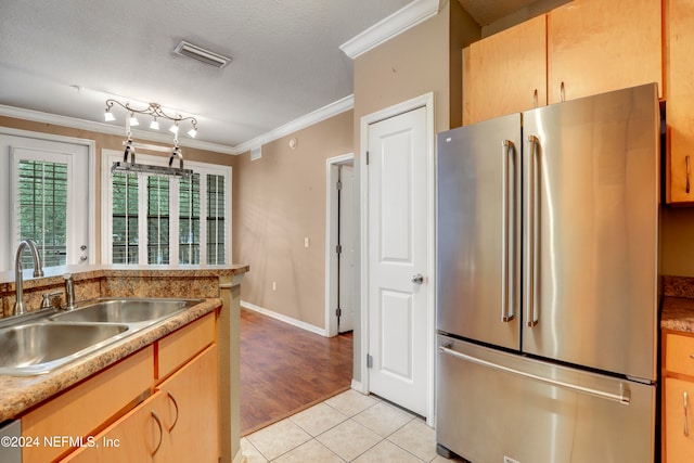 kitchen with sink, a textured ceiling, stainless steel fridge, light hardwood / wood-style floors, and crown molding